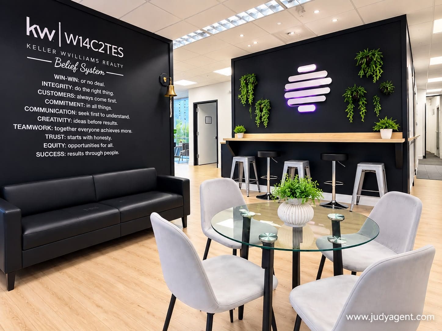 Lounge with a leather sofa beneath the Keller Williams Belief System wall, a glass table and a coffee bar