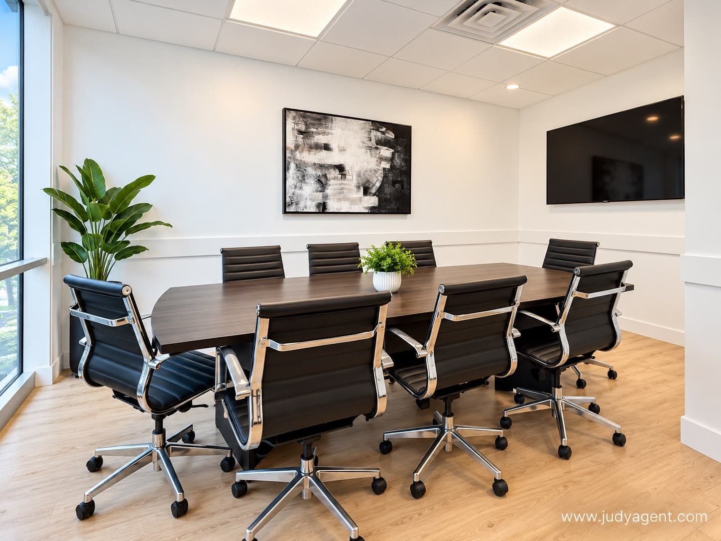Conference room with a long table, eight chairs and a wall-mounted screen